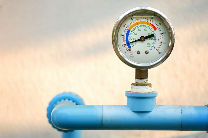 Water pressure gauge on blue plumbing pipe with natural blur background,  