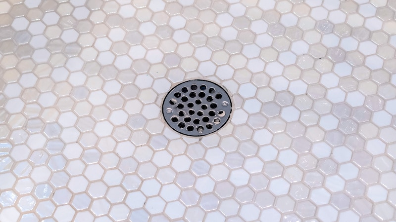 Panorama Drain plug in a shower cubicle floor. Drain plug in a shower cubicle floor covered in neutral colored small mosaic tiles in an interior decor and plumbing concept