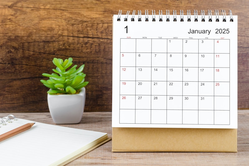 January 2025 desk calendar on wooden table.