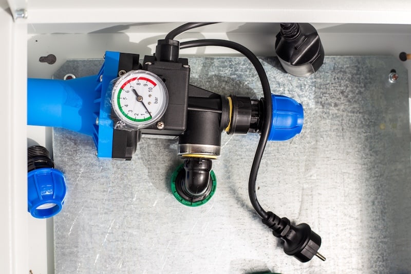 Automatic water supply regulator with pressure gauge in a metal box. Installation of drip irrigation system.