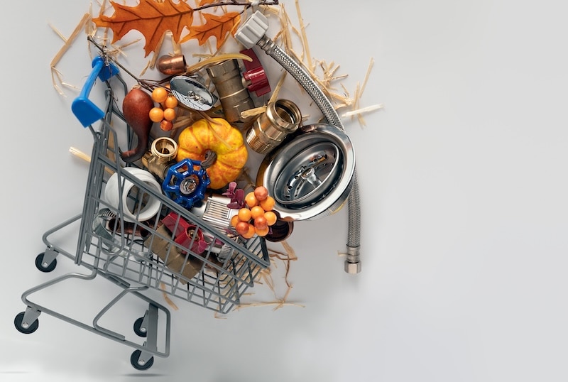 Plumbing Thanksgiving scene featuring a shopping cart filled with plumbing tools, construction equipment, maple leaves, and a pumpkin on a white background.