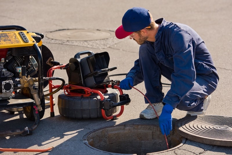 Plumber prepares to fix the problem in the sewer with portable camera for pipe inspection and other plumbing work.