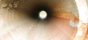 Workers install concrete pipes in a construction area with machinery.