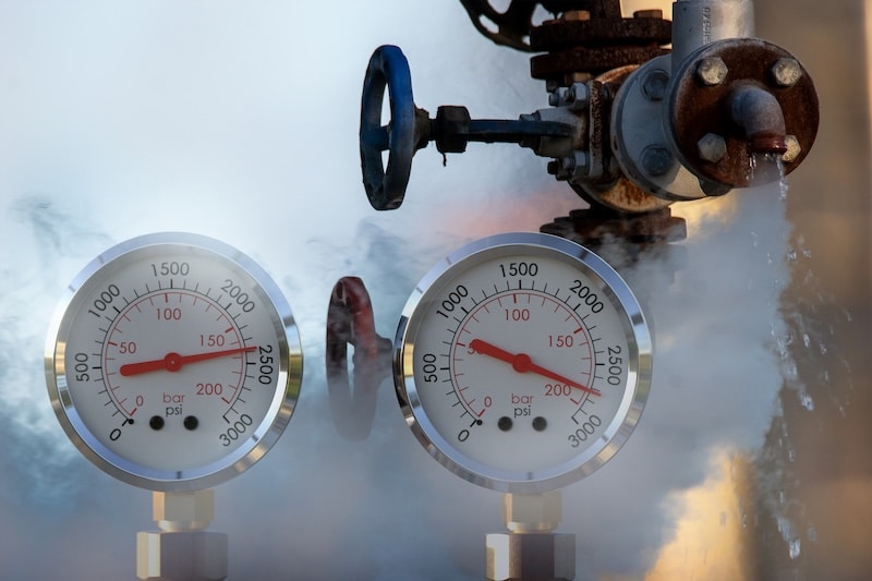 water pressure gauge meters against a leaky pipeline which comes out hot steam and hot water under pressure